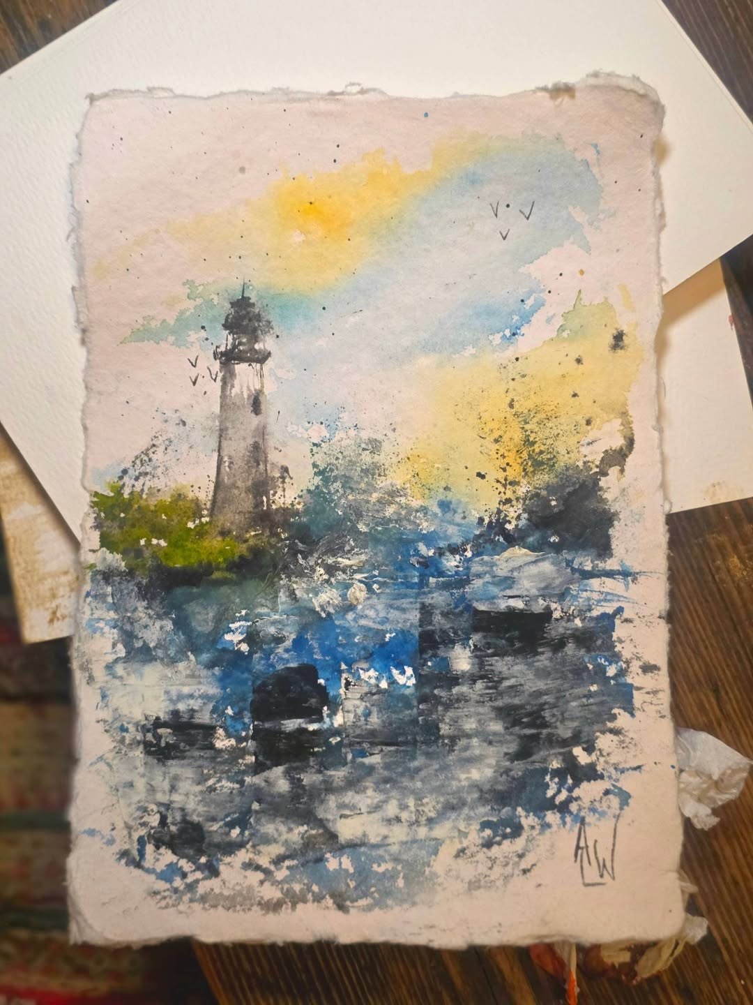 Watercolour painting of a lighthouse against a misty blue and orange sky